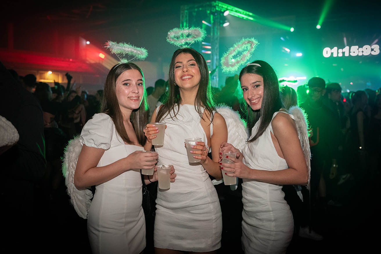 Tre ragazze in costume da angelo con drink all'evento di Halloween a Torino