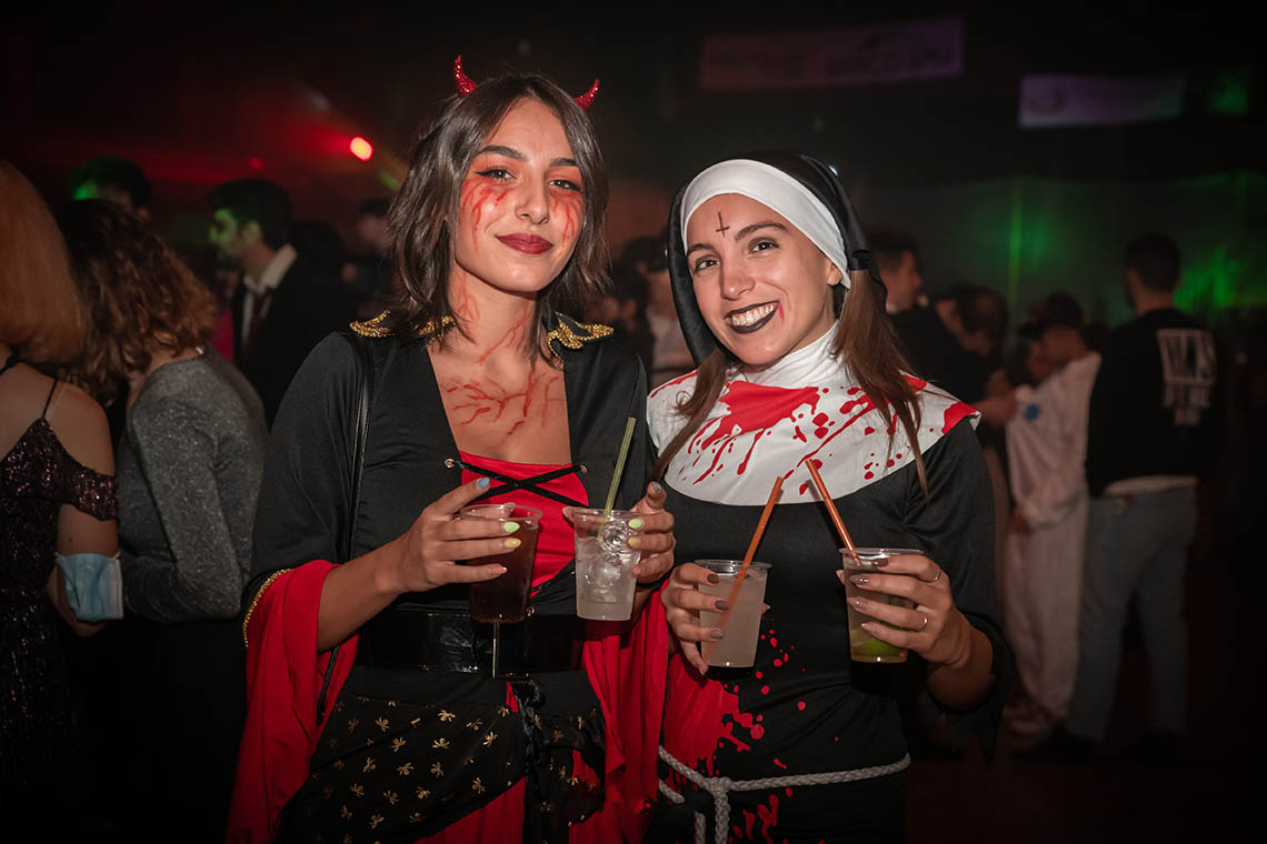 Due ragazze in costume da suora e diavoletta con drink all'evento di Halloween a Torino